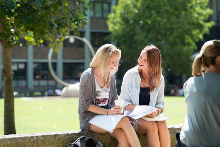 Two female students sitting by UNSW library lawn